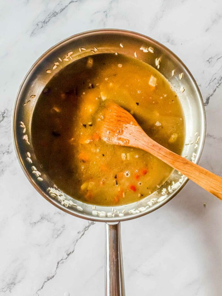 A skillet with broth to cook the rice pilaf in.