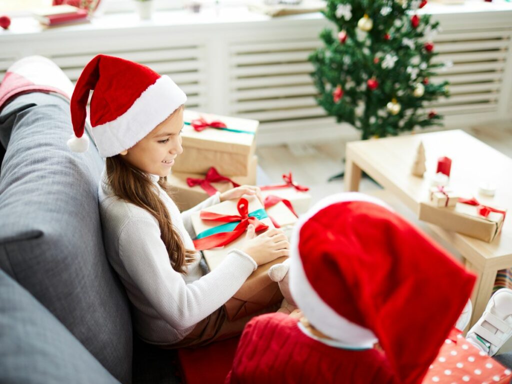 Two children in santa hats sitting on a couch.