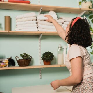 A woman is organizing towels in her laundry room, applying decluttering tips.
