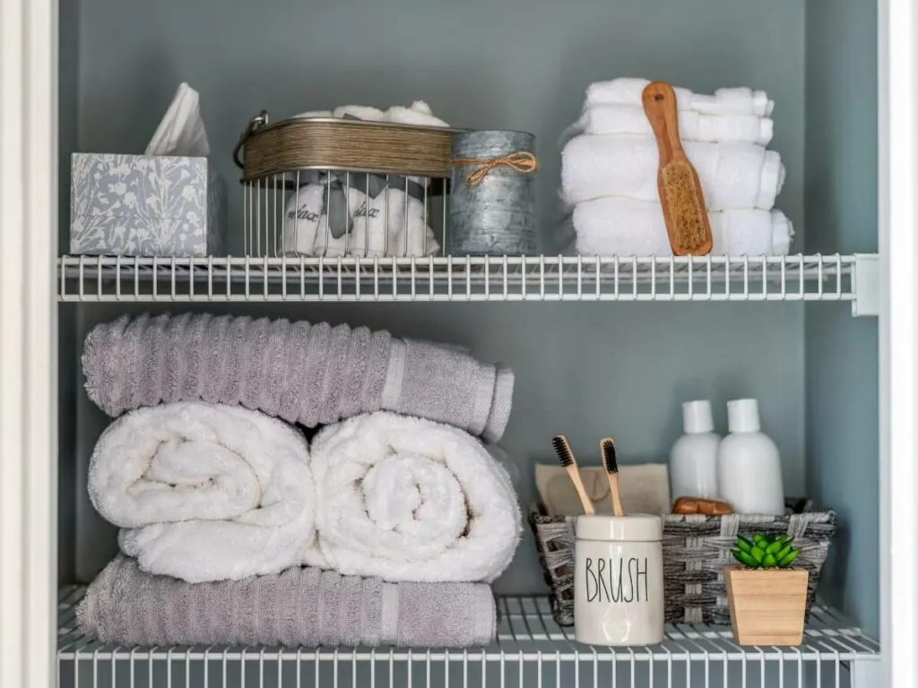 An organized bathroom shelf with towels, toiletries, and other items, after being decluttered.