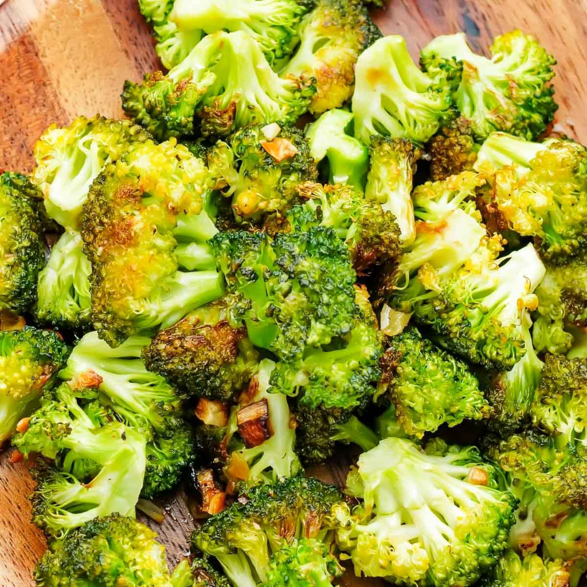 Roasted broccoli on a wooden plate.