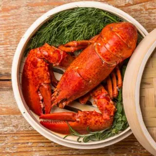A lobster in a bamboo basket on a wooden table.