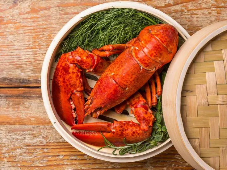 A lobster in a bamboo basket on a wooden table.