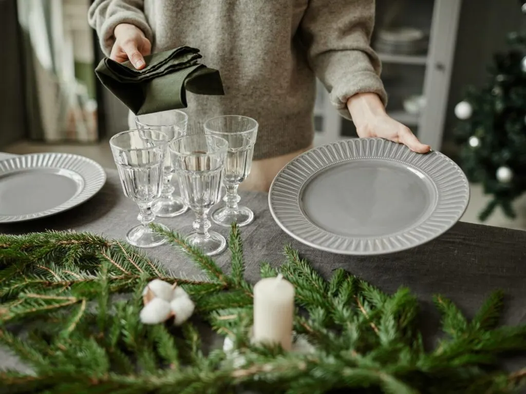 A woman demonstrates how to set a table for a Christmas dinner.