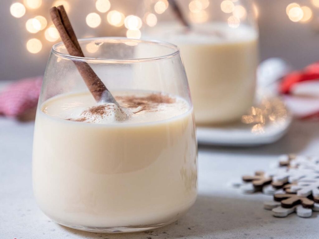 Two glasses of eggnog with cinnamon in them.