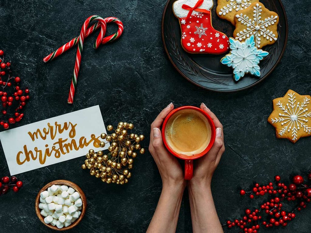 A woman holding a cup of Christmas blend coffee.