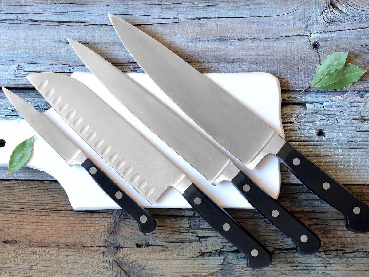 Four knives on a cutting board with leaves.