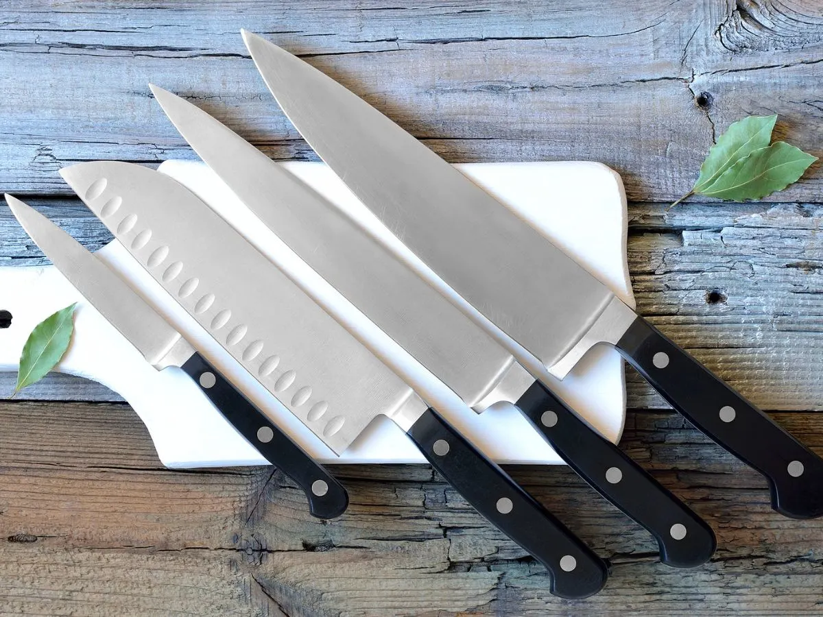Four knives on a cutting board with leaves.