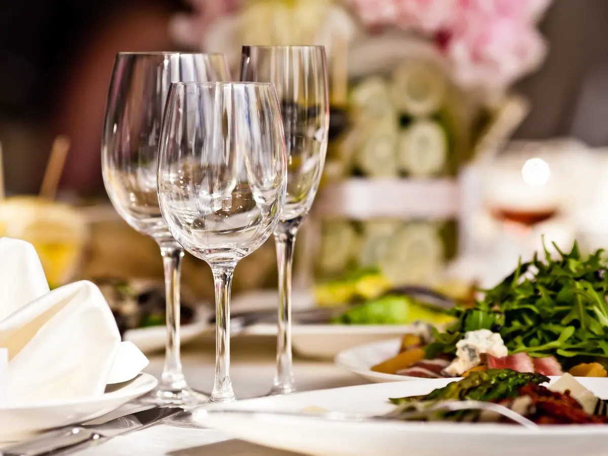 A table is set with wine glasses and plates of food.