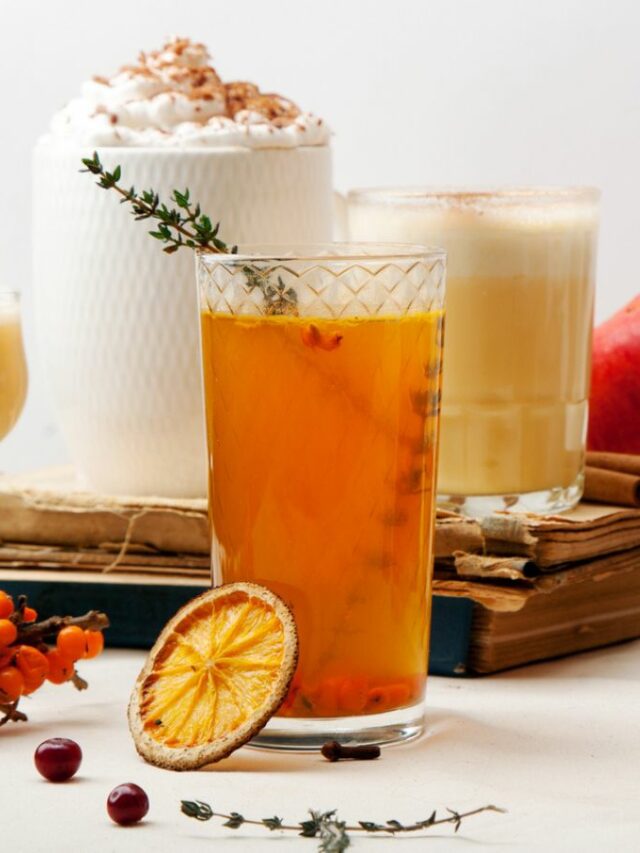 A glass of mulled wine and a cup of mulled cider on a table.