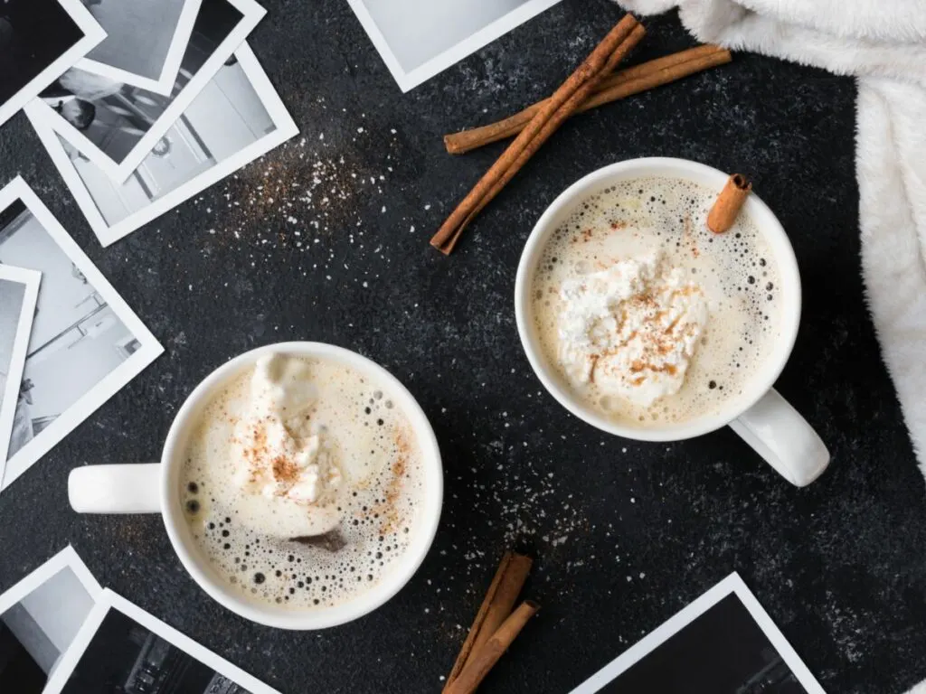 Two cups of eggnog coffee with cinnamon and whipped cream.
