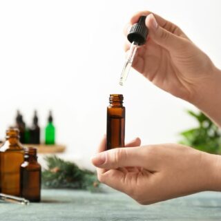 A person pouring essential oil into a glass bottle.