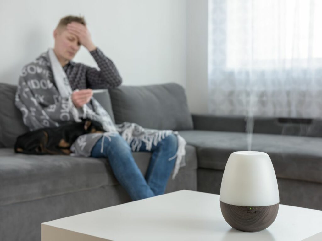 A man sitting on a couch with an essential oils diffuser.