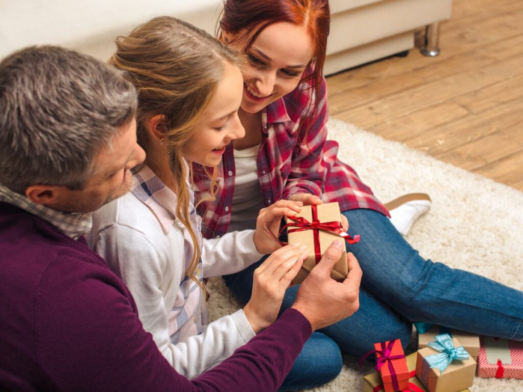 A family is opening a present on the floor.