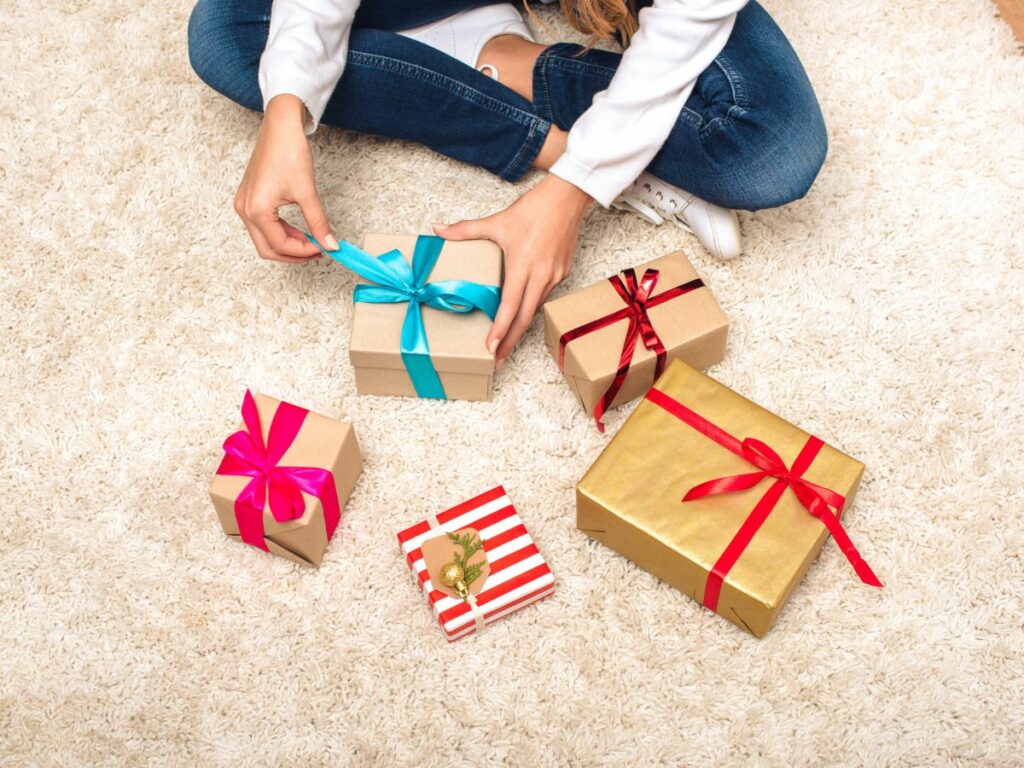 A teen girl is sitting on the floor with a gifts in front of her.