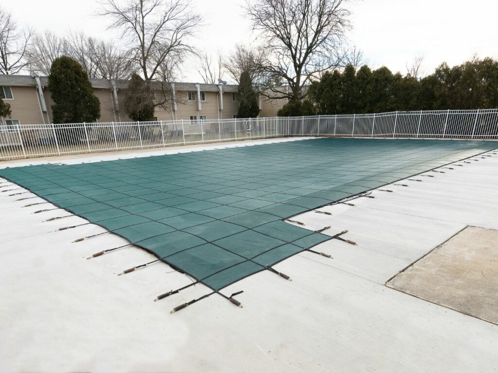 A swimming pool with a green cover on it in winter.