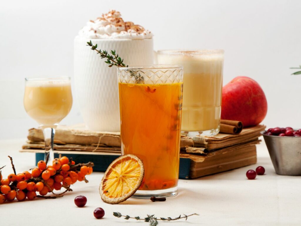 A table with several winter cocktail drinks and berries on it.