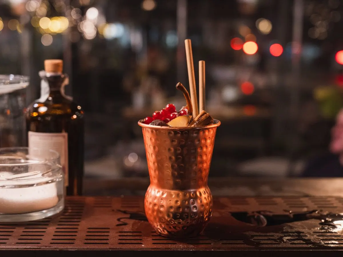 A copper mug with a holiday cocktail garnish on a bar.