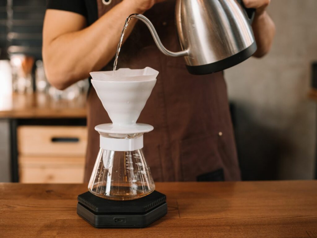 A man pouring water into a coffee maker filter.