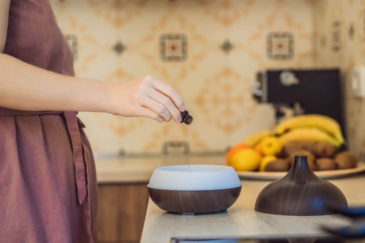 A woman adding essential oils to a diffuser.