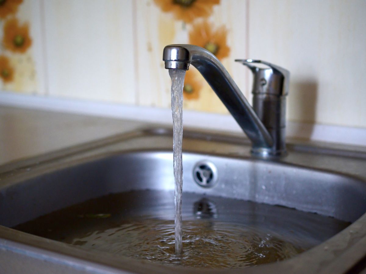 A clogged sink with running water from the faucet.