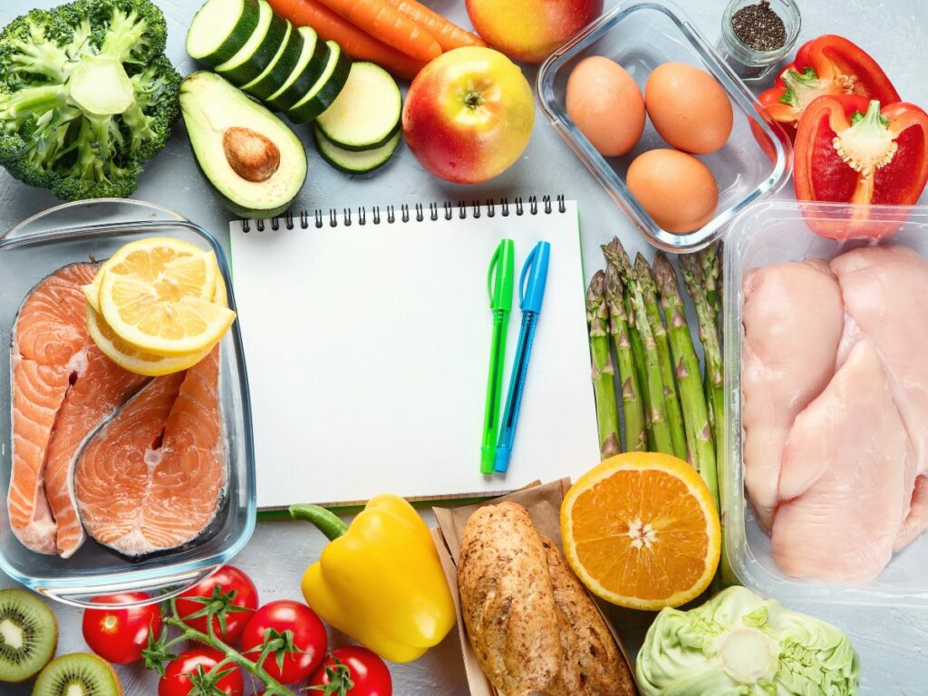 A notepad with a note about healthy eating is surrounded by a variety of foods.