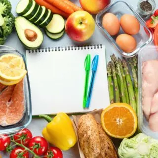 A notepad with a note about healthy eating is surrounded by a variety of foods.