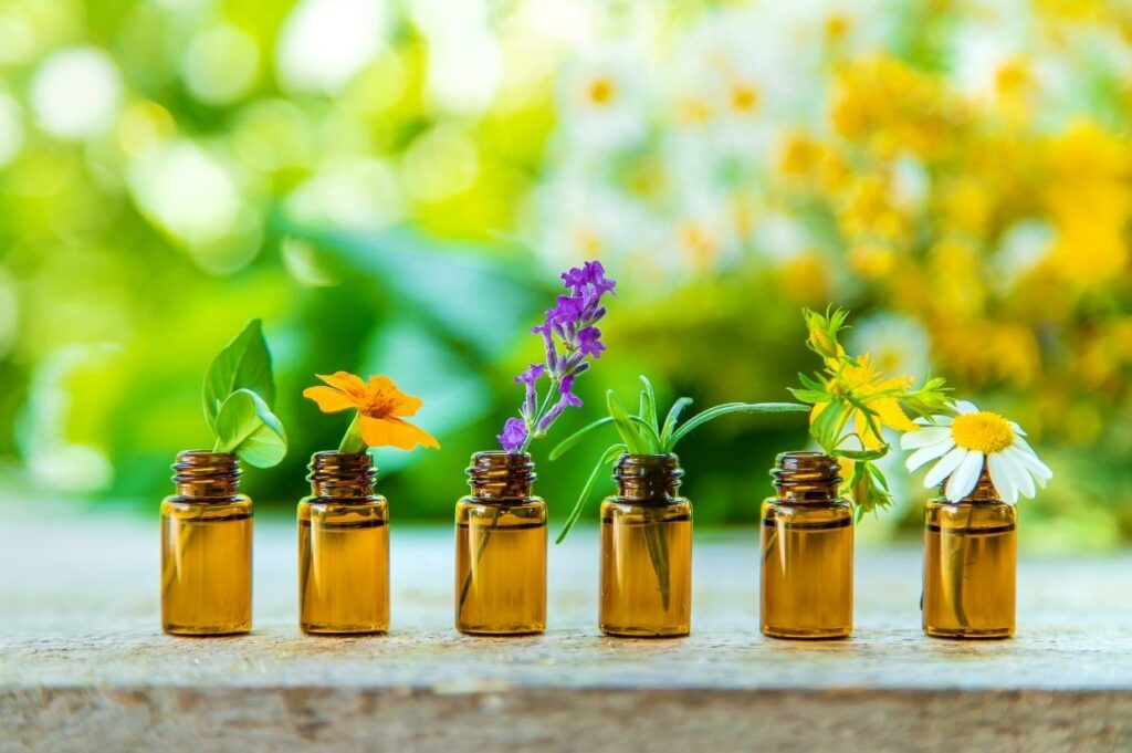Five bottles of essential oils with flowers in them.