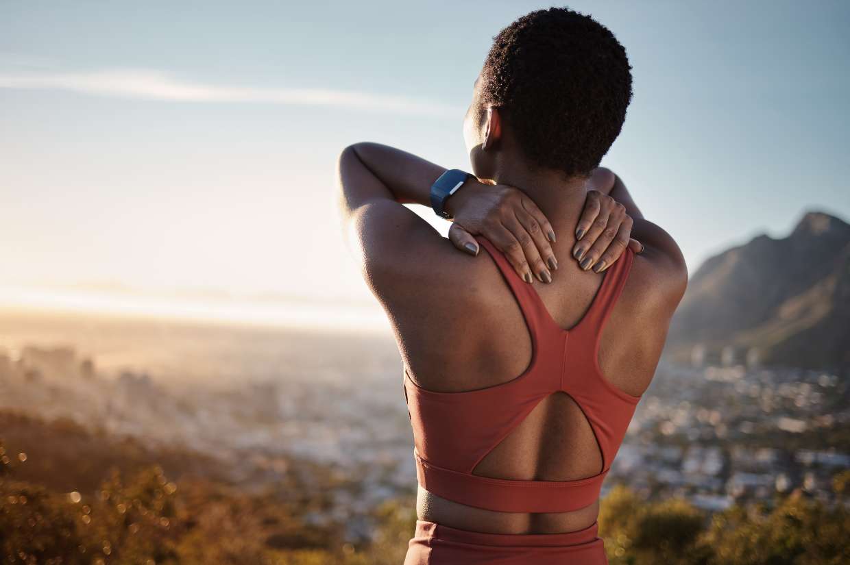 A woman stretches her back while looking at the view.