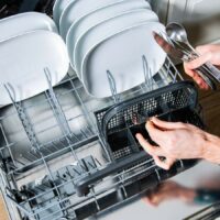 A man is putting dishes into a dishwasher.