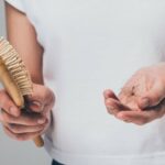 A woman holding a brush and a strand of hair.