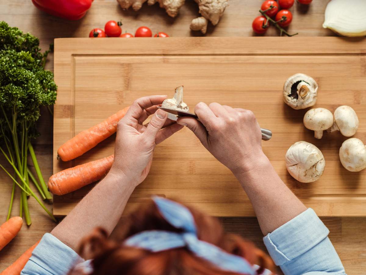 A woman is chopping vegetables on a cutting board.