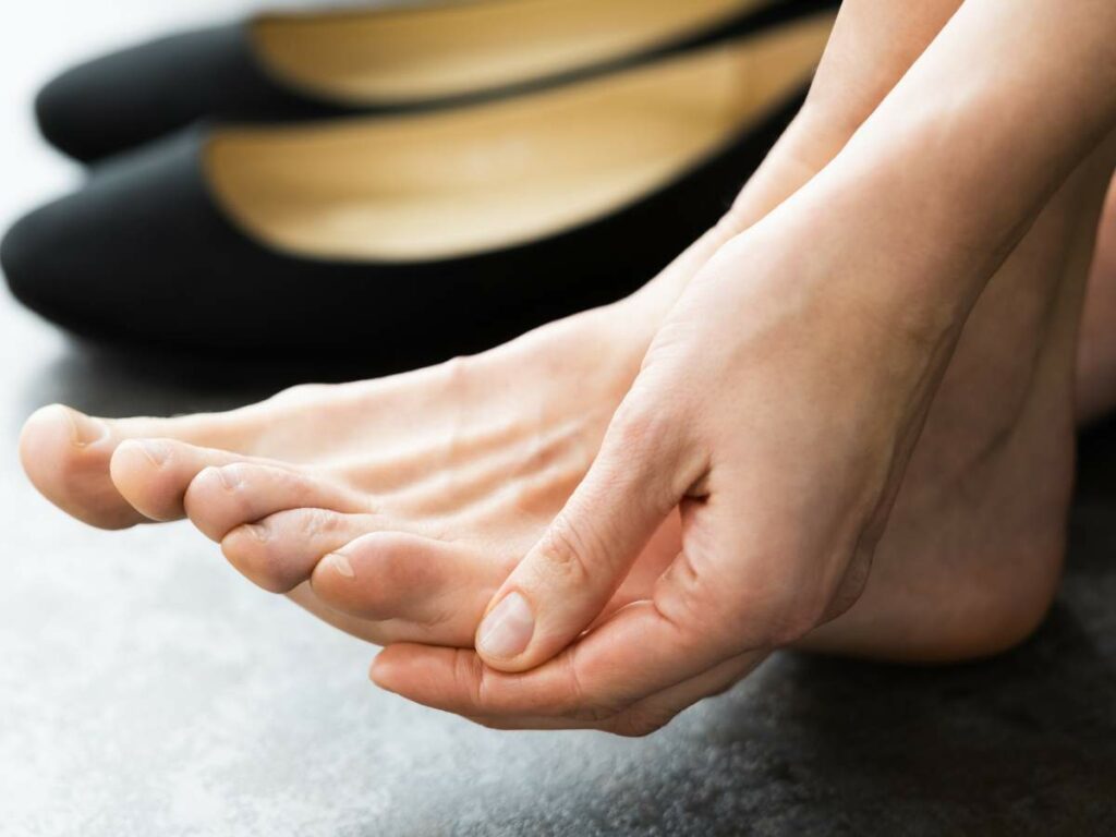 A woman's foot with a shoe near it.