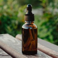 A bottle of essential oil sits on a wooden table.