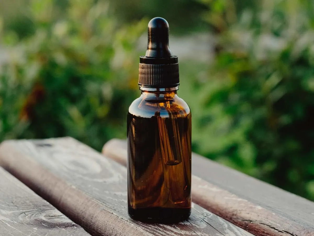 A bottle of essential oil sits on a wooden table.