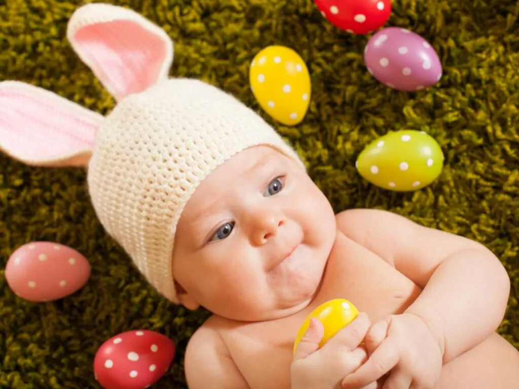 A baby lying on the grass with easter eggs.
