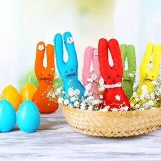 Colorful easter bunnies in a basket on a wooden table.