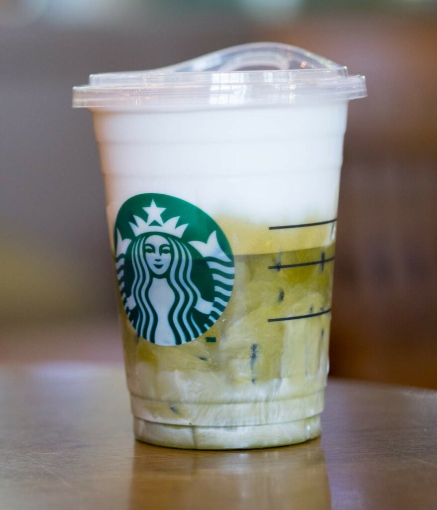 A cup of starbucks green tea is sitting on a table.