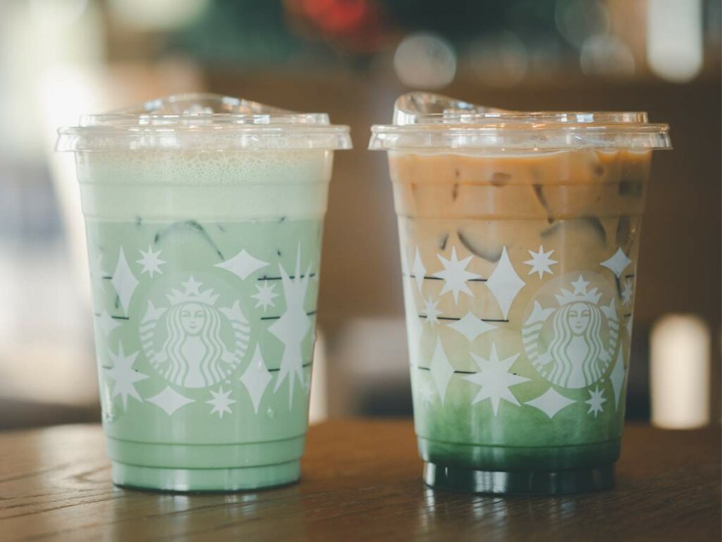 Two green starbucks drinks on a wooden table.