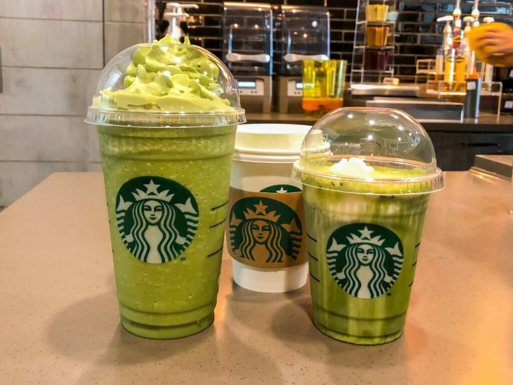 Three green starbucks drinks on a counter.