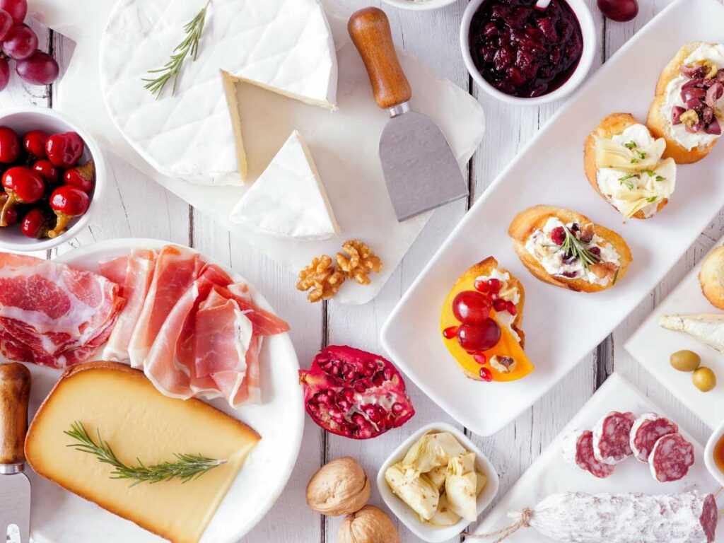 Assorted cheese and charcuterie platter with accompaniments on a wooden table.