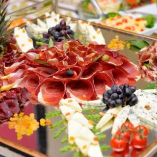 An assortment of cold cuts, cheese, and fruit arranged on a platter for a wedding.
