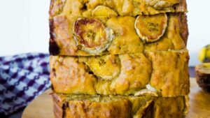 Close-up of a sliced loaf of banana bread with visible banana slices on the surface.