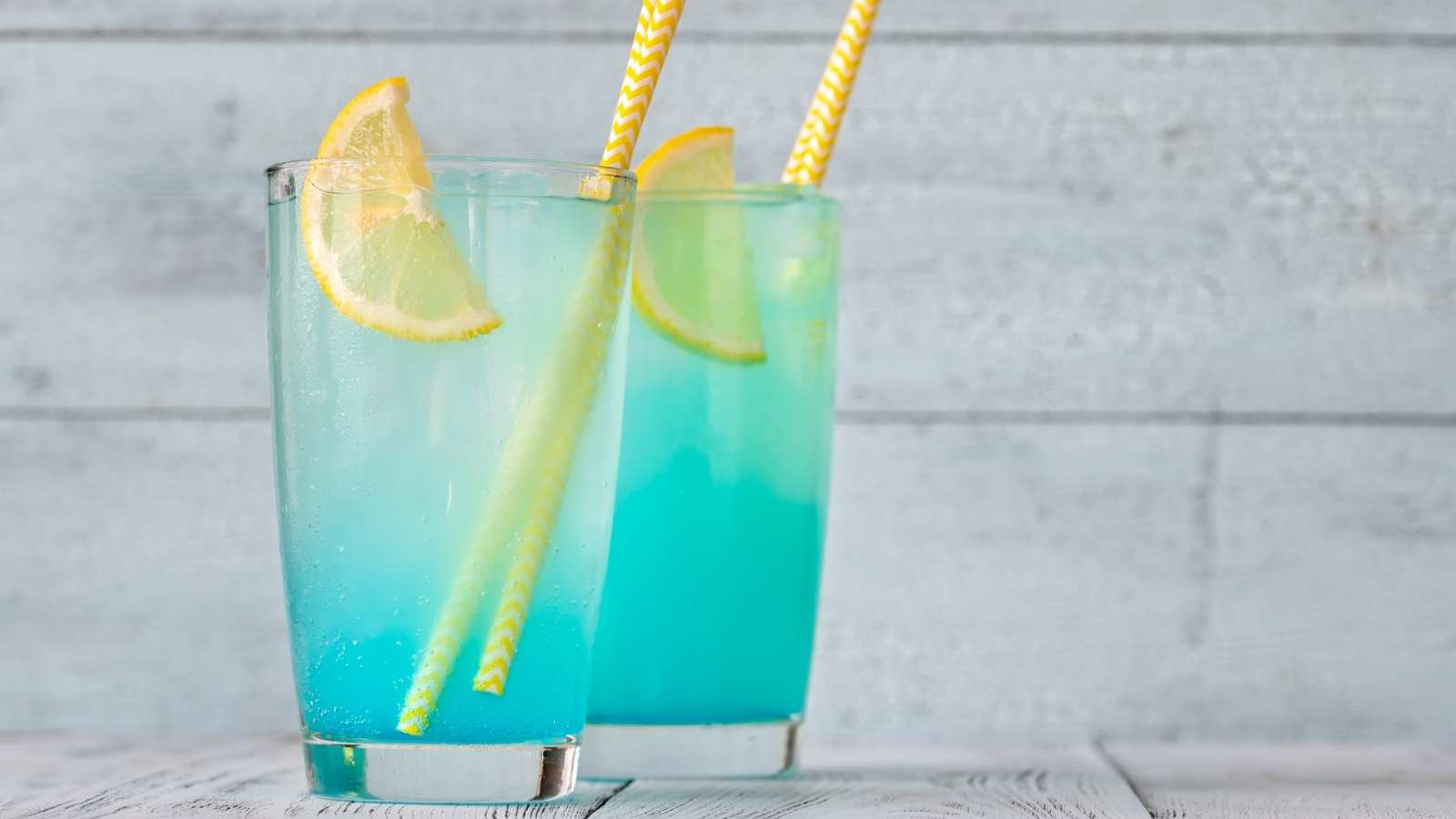 A picture of two glasses of electric lemonade with lemon wedge.