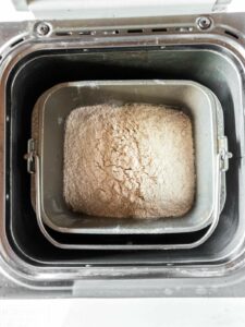 An open bread machine filled with flour mixture.