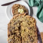 Close-up of a hand holding a slice of zucchini bread.