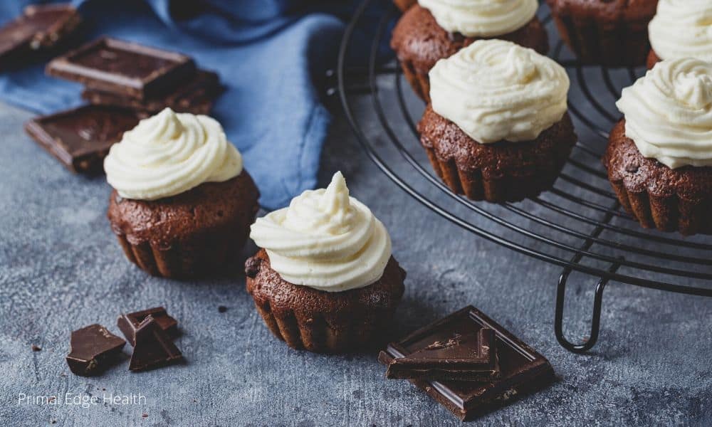 Chocolate cupcakes with buttercream frosting on a cooling rack.