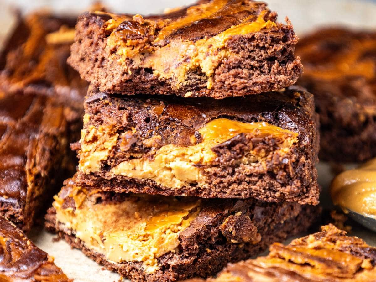 Six chocolate brownies with caramel swirls on parchment paper.