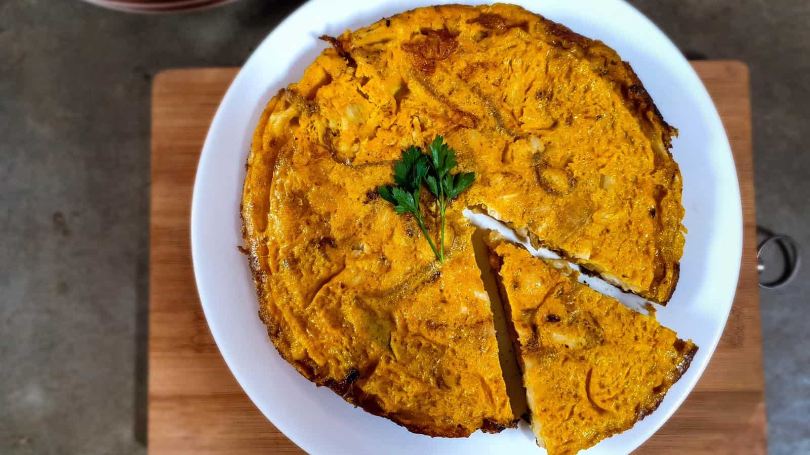 A picture of Spanish Omelette with Cauliflower and fresh parsley leaf.