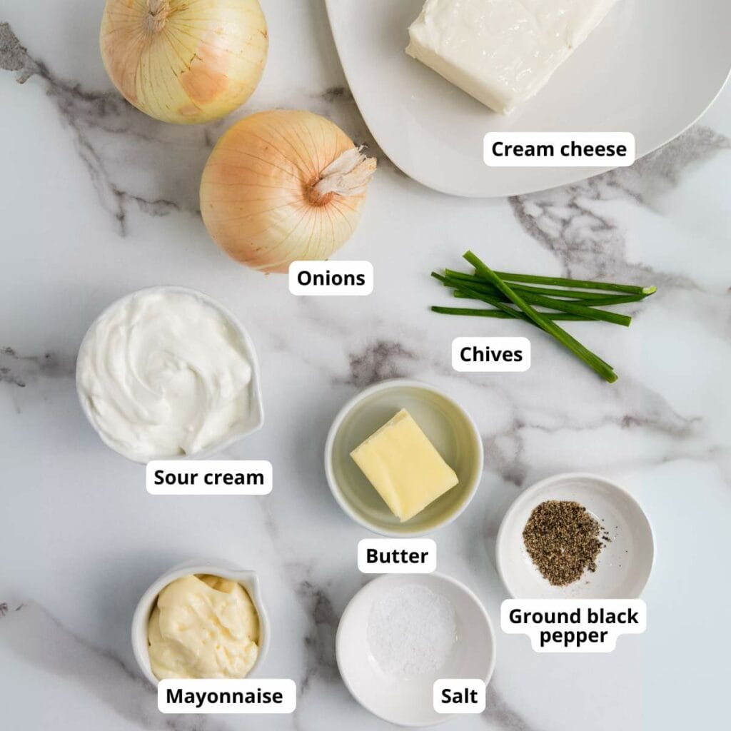 Ingredients for caramelized onion dip are arranged on a marble surface.